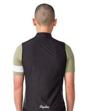Rapha Core Cycling Gilet worn by a model, back view with black gilet over a green Rapha cycling jersey and Rapha logo centered near the lower back