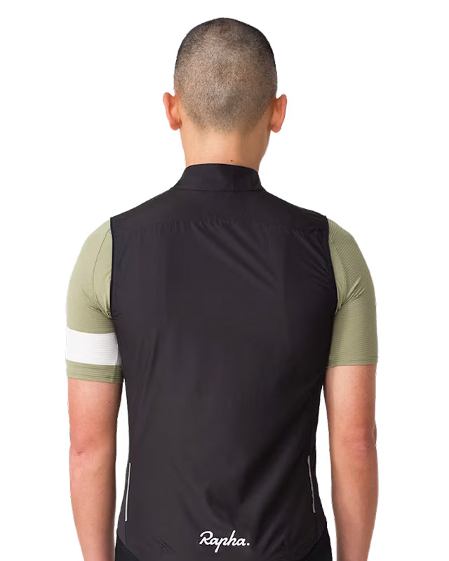 Rapha Core Cycling Gilet worn by a model, back view with black gilet over a green Rapha cycling jersey and Rapha logo centered near the lower back