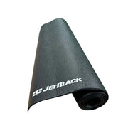 JetBlack Cycling trainer mat partially rolled on white background with the white JetBlack logo visible and textured black surface showing.