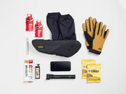 Flat lay of cycling essentials arranged beside the Trek Adventure Triangle Bag 1L to show its storage capacity.