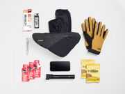 Flat lay of cycling gear arranged beside the Trek Adventure Triangle Bag 1.3L to illustrate its storage capacity.