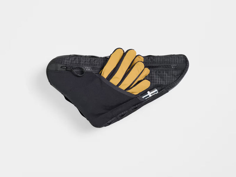 Rear view of the Trek Adventure Triangle Bag 1.3L showing the back pouch with cycling gloves and accessories partially tucked inside.