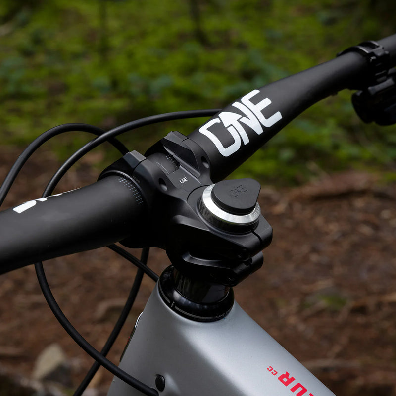Close-up of a bicycle handlebar with 'ONE' branding against a natural background