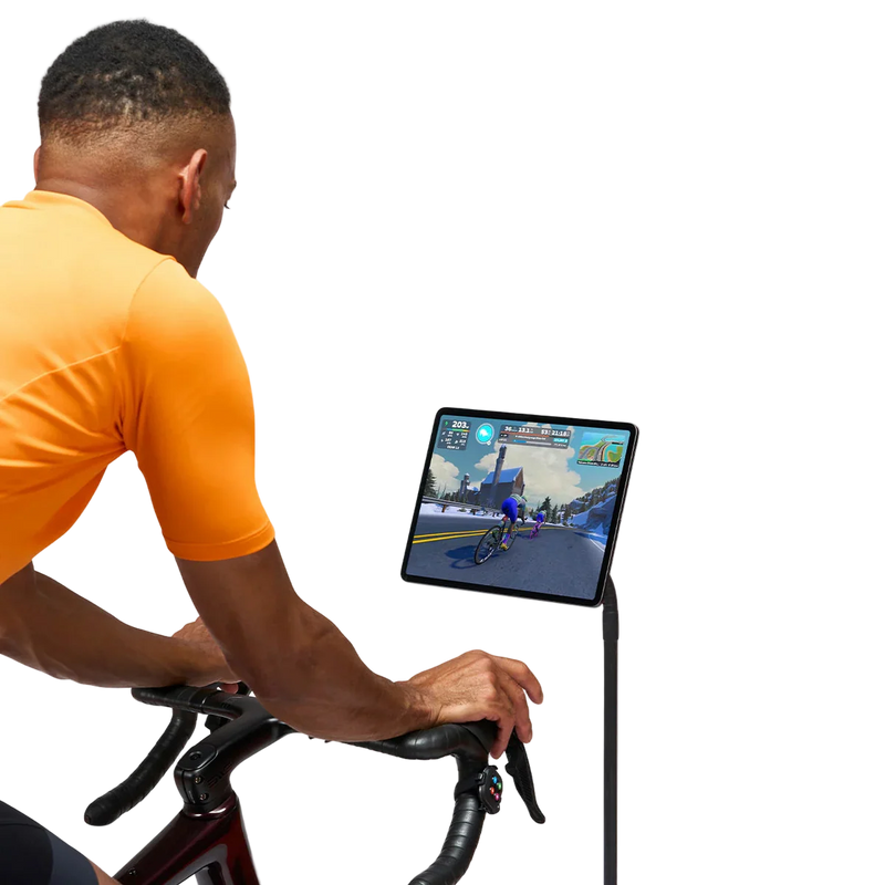 Rider using Zwift Click V2 while cycling indoors with a screen in front