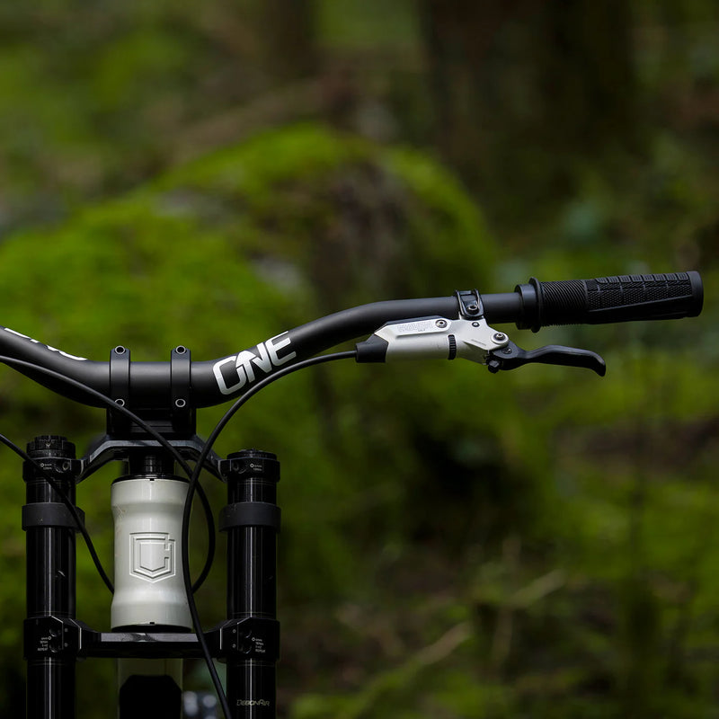 Close-up of a bicycle handlebar with 'ONE' branding against a blurred green background