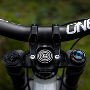 Close-up of a bicycle handlebar with 'One' branding against a blurred green background