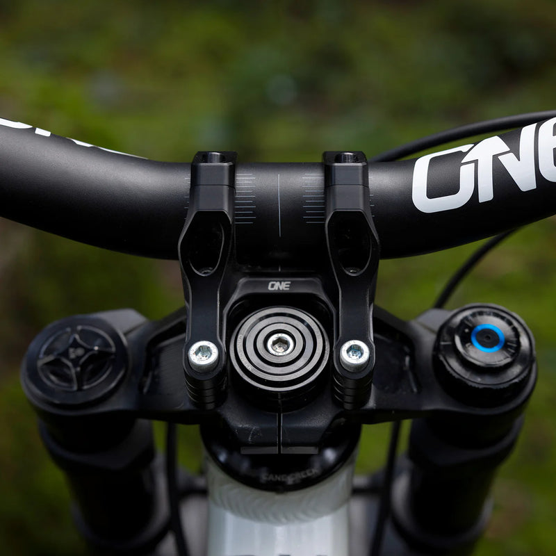 Close-up of a bicycle handlebar with 'One' branding against a blurred green background