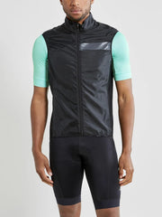 Craft Essence Light wind vest in black worn over a cyan jersey, front view