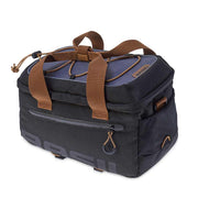 Basil Miles Trunk Bag 7L in Black Slate, three-quarter front view showing the rectangular bag, BASIL branding, side zippered pocket, brown and black strap details, brown mounting straps and elastic cord with drawstring closure on top