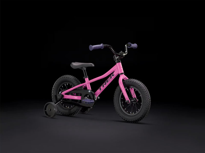 Pink balance bike with training wheels on a black background