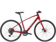 A red Trek hybrid fitness bicycle with black components, tires, and saddle, shown from a side profile view against a solid white background.