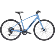 A light blue hybrid fitness Trek bicycle with black components, black tires, and a black saddle, shown from a side profile on a solid white background.