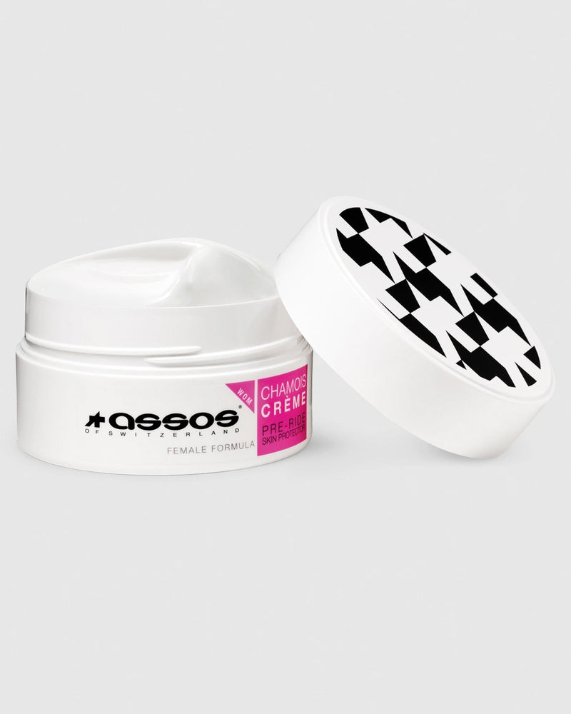 White jar of 'Assos Chamois Crème' with black and white checkered lid on a light gray background