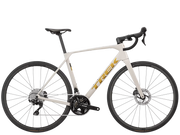 A white Trek road bicycle with black components and gold logo detailing, shown from a side profile view against a solid white background.