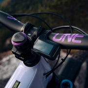 Close-up of a bicycle handlebar with a digital display and purple 'UVE' branding.