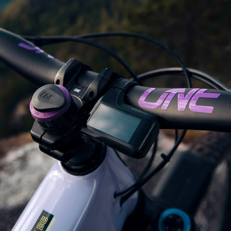Close-up of a bicycle handlebar with a digital display and purple 'UVE' branding.
