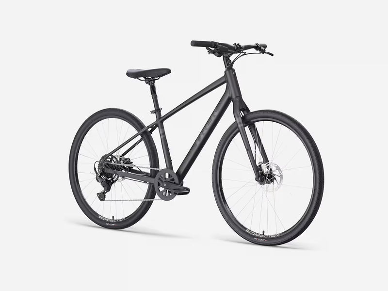 A matte black stepover cruiser electric bicycle with a step-through frame, front suspension fork, and integrated rear rack, shown from a three-quarters front angle on a light gray studio background.
