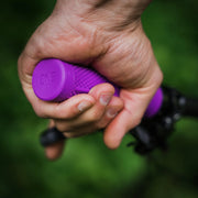 Hand holding a purple tool with 'ONE' branding against a blurred green background