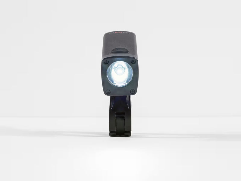A black tactical LED bike light with its front light illuminated, standing vertically on a white surface against a white background.