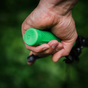 Hand holding a green handle with 'ONE' branding against a blurred green background