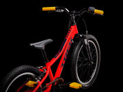 Red children's bicycle with black frame and yellow handlebar grips on a black background