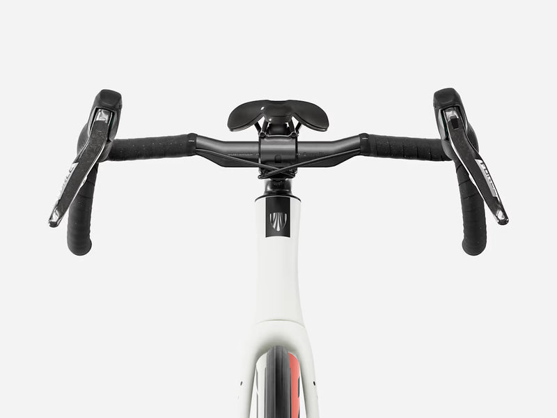 Close-up front view of a drop-bar endurance road bicycle handlebar setup with black grips, black saddle and handlebar components, mounted on a white bicycle frame against a light gray studio background.