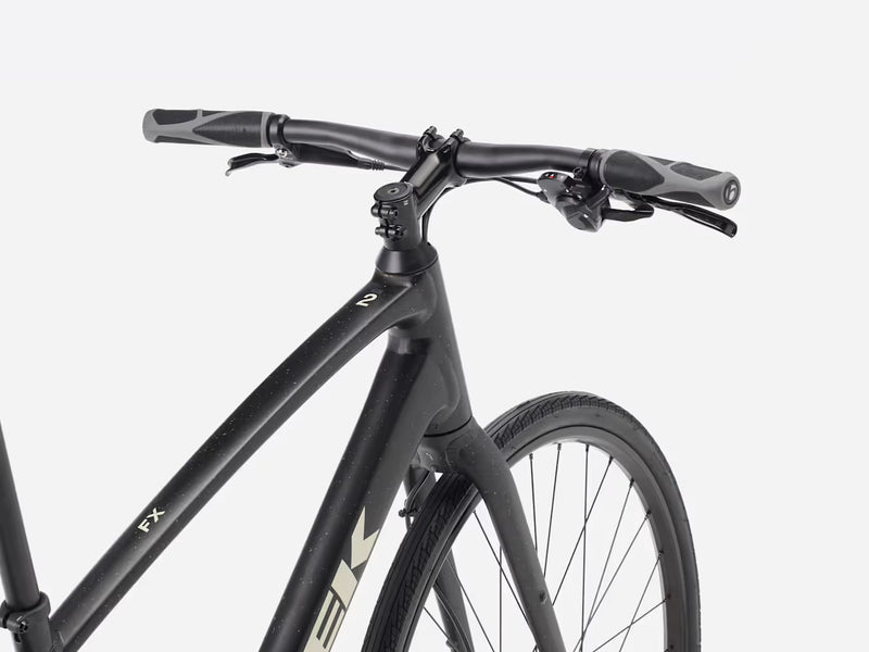 Black hybrid fitness bicycle with brand logo \Trek' and product name 'FX' visible, against a white background