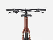 Front view of a cruiser bicycle with a matte brown/light red frame, black handlebars, and a black saddle, shown against a light gray background.