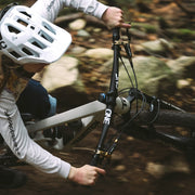 Person adjusting a bicycle in a forest setting