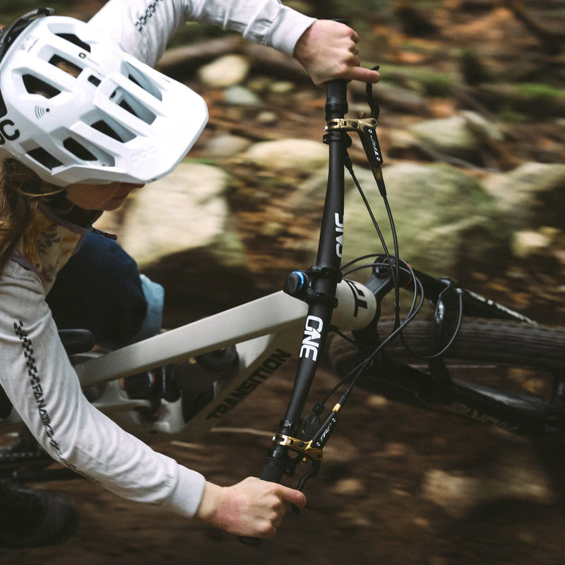 Person adjusting a bicycle in a forest setting