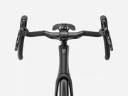 Front view of a black drop-bar road bicycle handlebar setup with Shimano route bar levers and a black saddle, shown on a light gray background.
