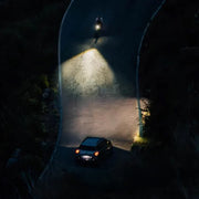 lifestyle image of cyclist on windy road and a car, demonstrating the wide light of Magicshine bike light