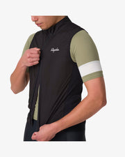 Rapha Core Cycling Gilet worn by a model, diagonal front view showing the zipper being closed over a green Rapha cycling jersey