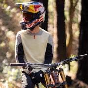 Person wearing a Red Bull helmet and riding a mountain bike in a forest