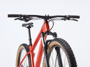 Orange bicycle with black components on a light gray background