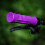 Close-up of a purple bicycle handlebar grip with a blurred green background