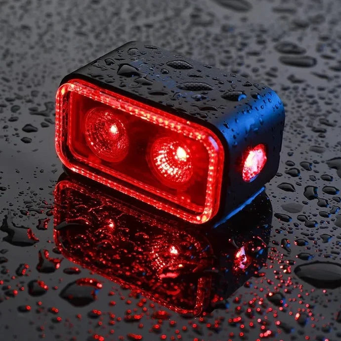 Lifestyle close-up of the Magicshine Seemee 300 taillight illuminated in red on a bicycle in the rain
