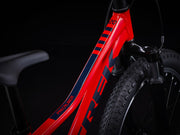 Close-up of a red bicycle with 'Trek' branding on a black background