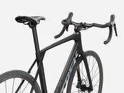 Trek Domane SL 4 Gen 5 in Matte Deep Smoke, rear three-quarter view showing Domane frame logo, Bontrager Paradigm wheels, handlebars, and Trek bar-end detail