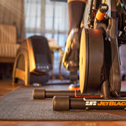 Lifestyle image in a living room with the JetBlack Victory trainer and stabilizer legs visible, background softly blurred.