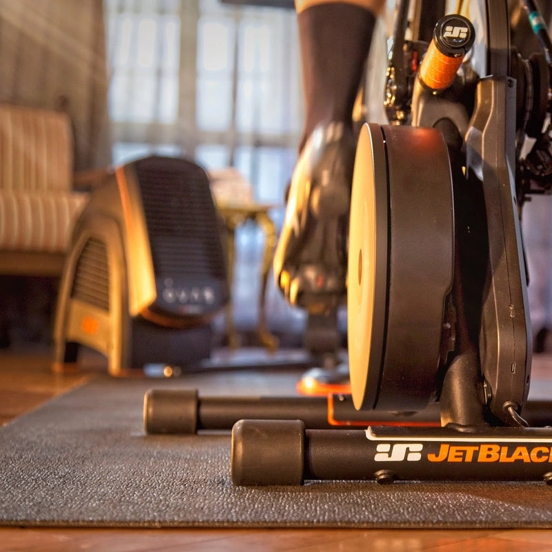 Lifestyle image in a living room with the JetBlack Victory trainer and stabilizer legs visible, background softly blurred.