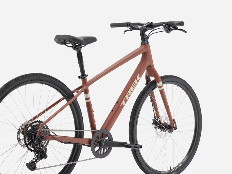 A Trek cruiser bicycle with a matte terracotta red brown frame, black handlebars, saddle, and tires, displayed on a clean light gray background.