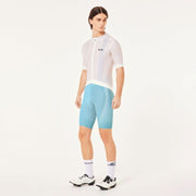Person wearing a white cycling jersey and light blue shorts on a white background