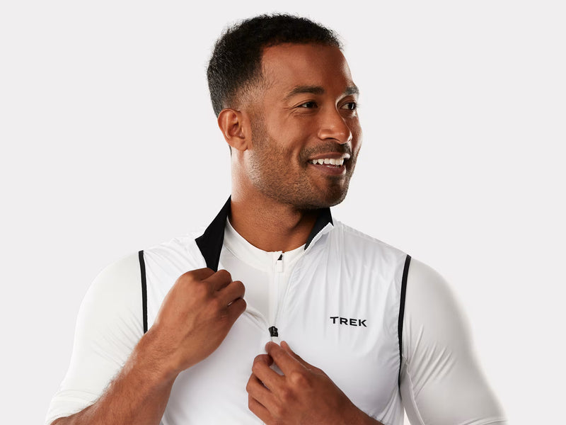 Man wearing a white cycling jersey with 'Trek' branding on a light gray background