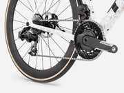 Close-up of a bicycle's rear wheel, chainring, crankset, and derailleur on a light gray studio background. The wheel is black with a beige tire wall, and the crankset is dark gray/black with a visible 'FORCE' brand mark.