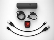 Collection of electronic components including a power bank, USB cables, and a red light device on a white background.