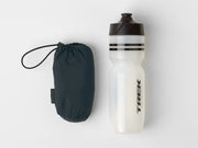 Jacket rolled up into its storage pouch, shown beside a water bottle to demonstrate its compact size.