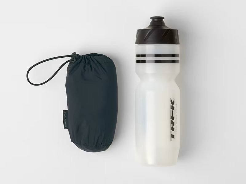Jacket rolled up into its storage pouch, shown beside a water bottle to demonstrate its compact size.