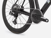Close-up of a black endurance road bicycle drivetrain showing the rear wheel, chainring, chain, cassette, and crankset with a visible Force brand mark on the arm.