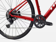 Close-up of a red hybrid fitness bicycle with chain and gear system on a white background